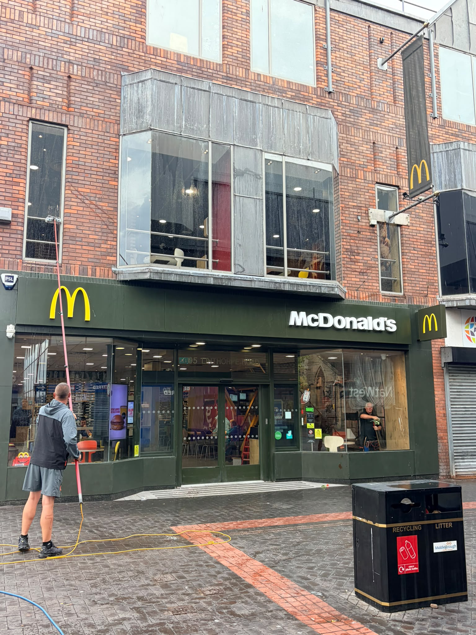 A cleaner using a water-fed pole on the upper windows of a McDonald's