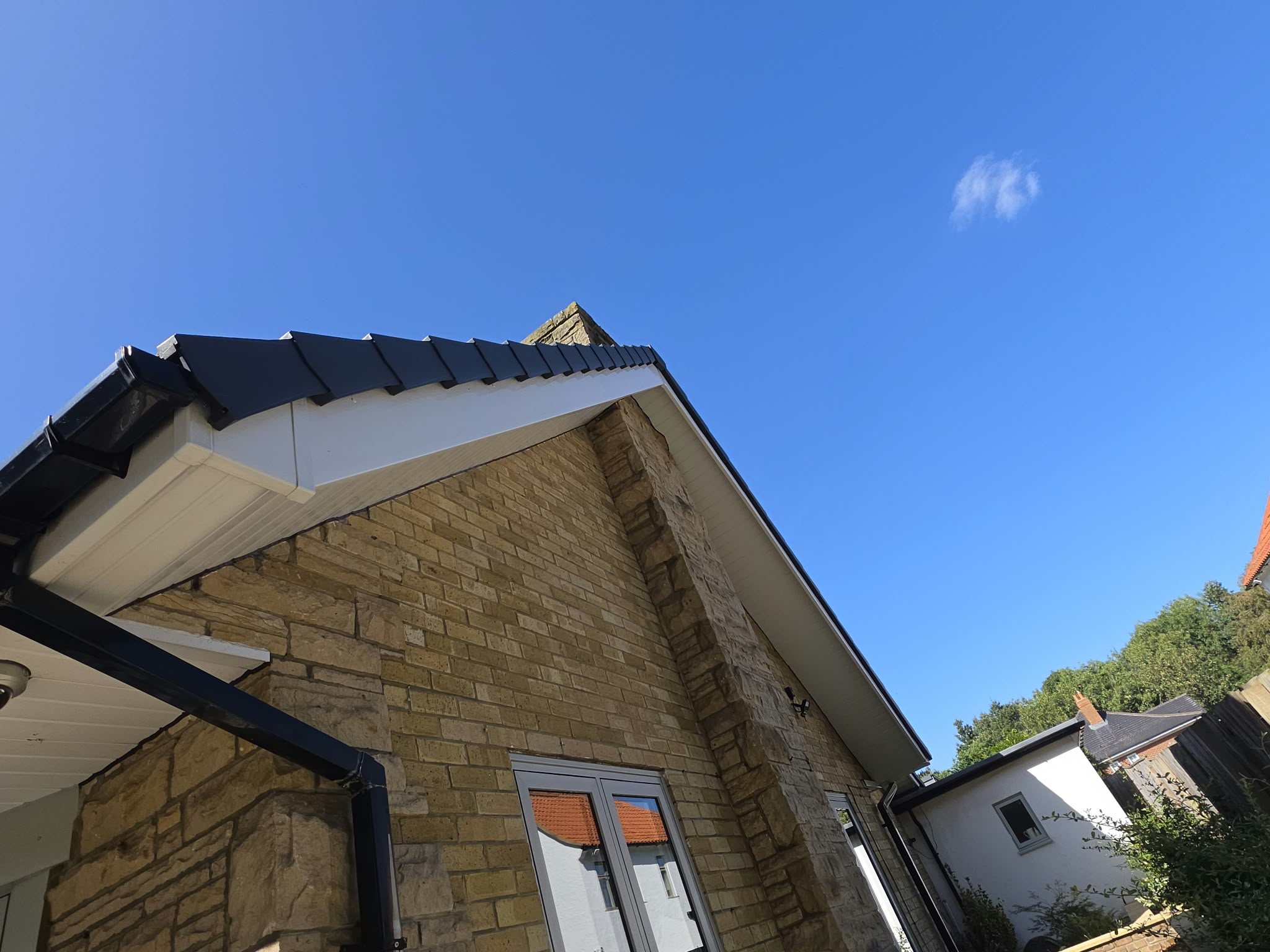 White gable fascia and black guttering on a stone house