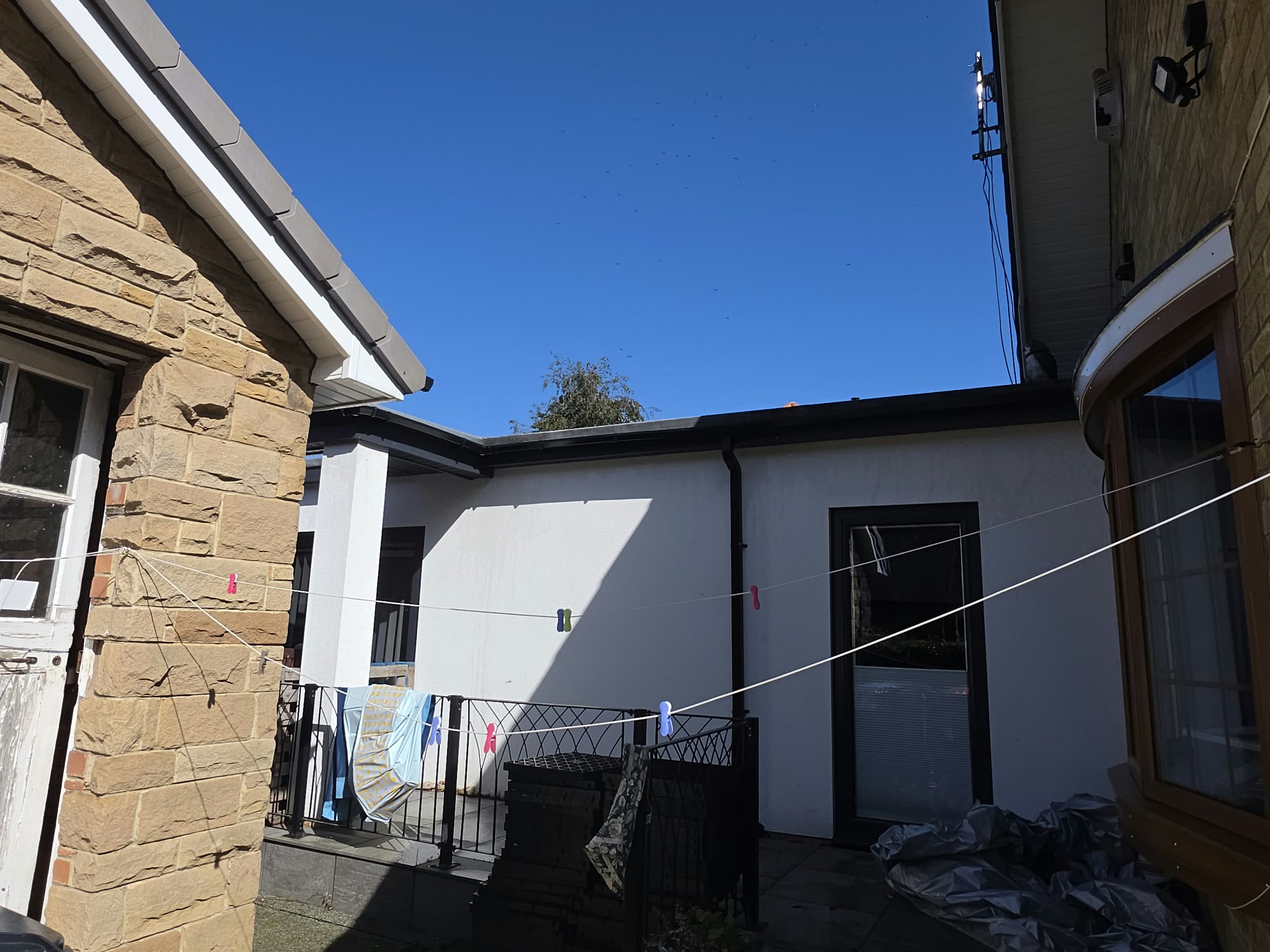 Black gutter and downpipe along the rear extension between two houses